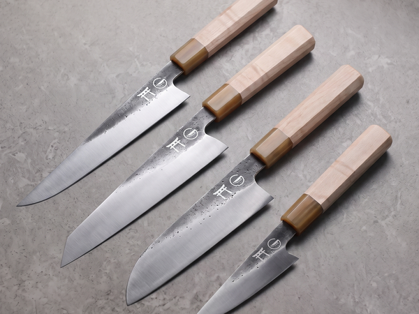 Four hand-forged Torii kitchen knives of different blade lengths laid side by side