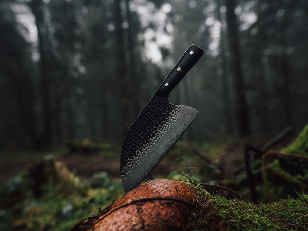 Hand-forged kitchen knife blade being shaped, showing the tapered spine of a forged knife